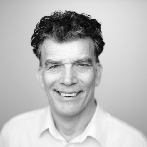Porträt von Alfred Sonnleitner mit lockigem, dunklem Haar und weißem Hemd – lächelt freundlich in die Kamera, neutraler Hintergrund